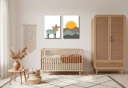 A bright, minimalist Boho nursery with cream-colored walls and soft natural lighting. Two canvas prints hang above a light wood crib: one features a donkey wearing a sombrero, and the other a minimalist sun setting over rolling hills. To the right is a tall rattan cabinet or armoire. To the left is a macrame wall hanging and a small wooden side table with a vase of pampas grass and children's toys.