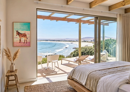 Modern bedroom with a large sliding glass door leading to a patio with ocean views and a mexican donkey wall print.