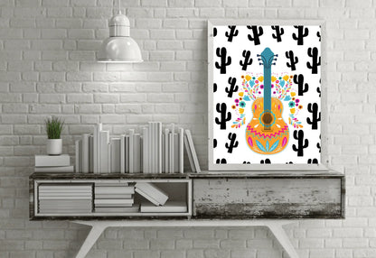 A framed boho folk art guitar print with a black cactus background, hanging on a white brick wall above a weathered wooden console table with books and a plant.