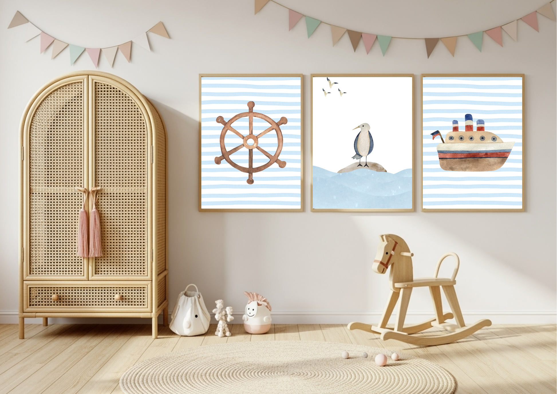 Three framed nautical-themed wall art prints hang on a light wall in a styled nursery. The prints feature a wooden ship's wheel, a penguin on ice, and a cruise ship on blue-and-white striped backgrounds.