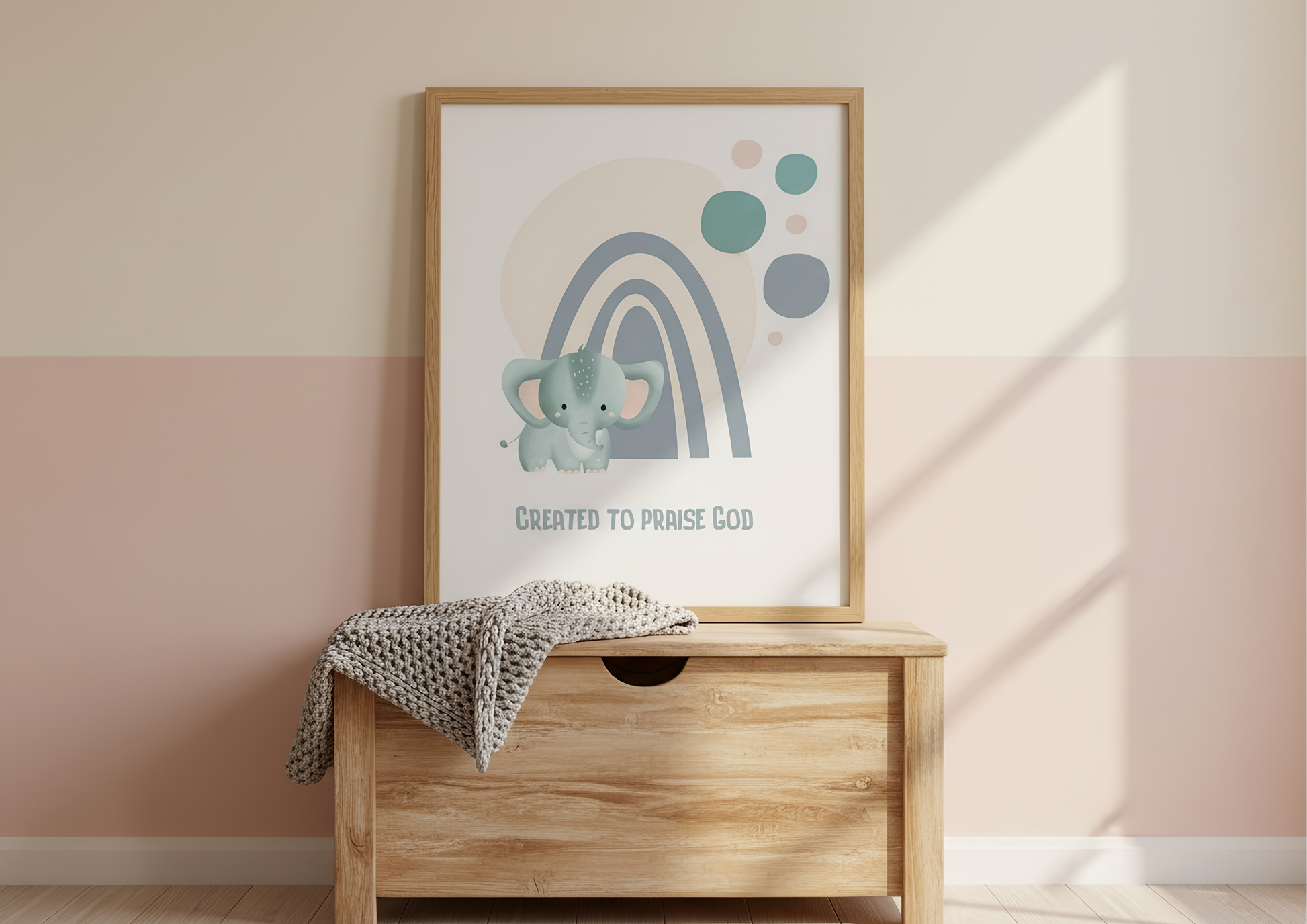 Framed artwork with an elephant and rainbow on a wooden dresser against a pink wall.