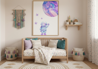 A gender-neutral nursery featuring a wooden crib with a constellation blanket and purple/teal pillows. A large framed watercolor art of an astronaut and a purple planet hangs above the crib. A macrame planet wall hanging is on the left.