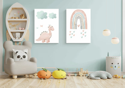 Two framed pastel prints (pink dinosaur with clouds, and a rainbow with hearts) on a light blue wall in a child's playroom with a rocket shelf.