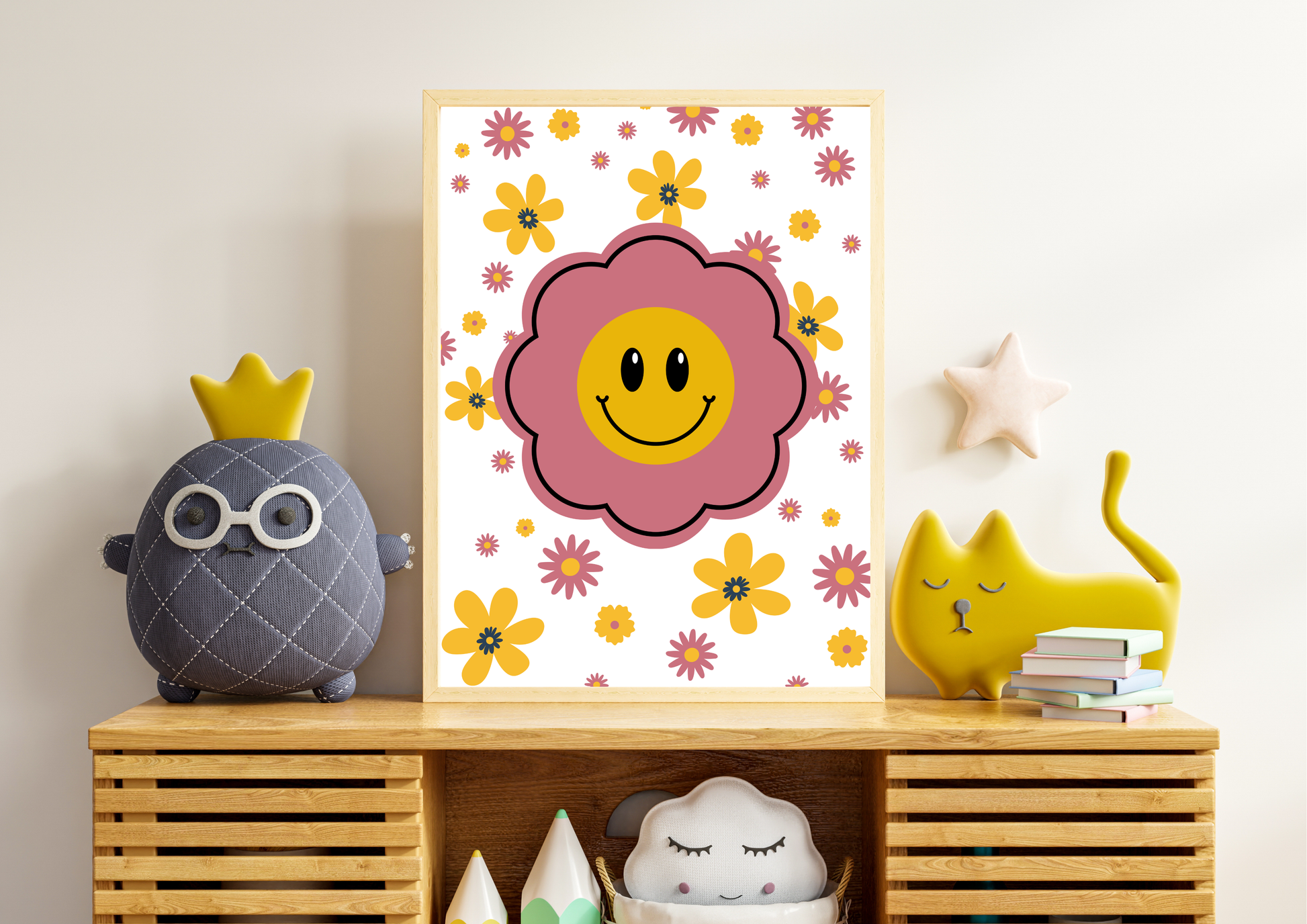 A framed art print featuring a smiling flower face surrounded by small colorful flowers, styled on a wooden shelf with a gray plush character, a yellow cat figurine, and other nursery decor.