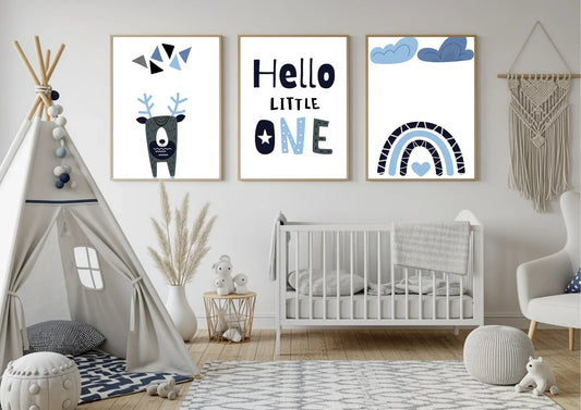 A children's room with a white teepee tent on the left and a white crib on the right. There are three framed prints on the wall featuring a geometric deer, the text "Hello LITTLE ONE," and a blue rainbow.
