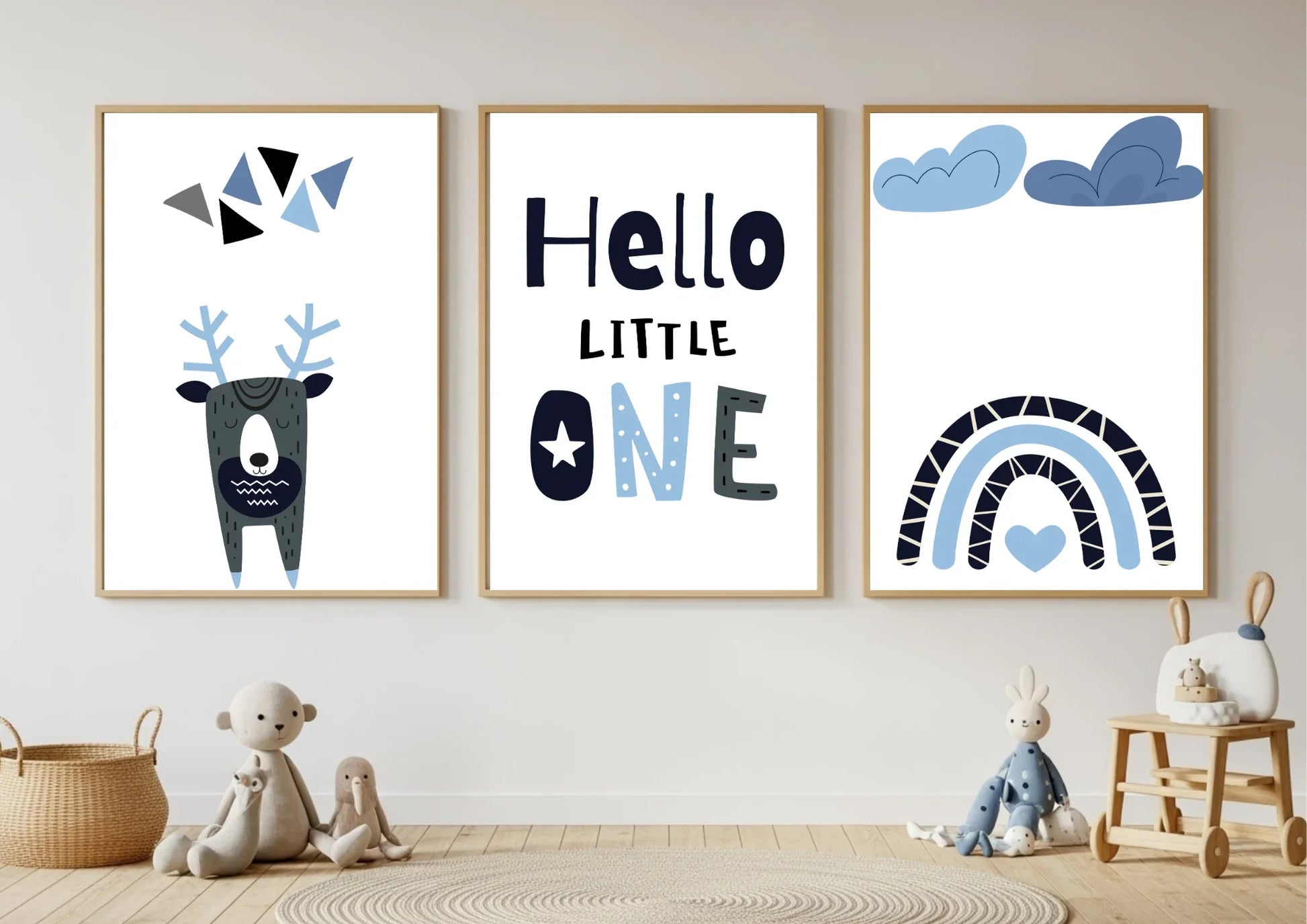 Three framed prints on a wall with toys below, featuring a deer, text, and rainbow designs.
