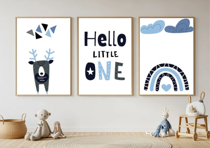 Three framed prints on a wall with toys below, featuring a deer, text, and rainbow designs.