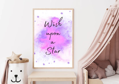 A framed "Wish upon a Star" nursery print with a purple and pink watercolor galaxy and stars, hanging on a white wall above a wooden table and a white bed with a canopy.