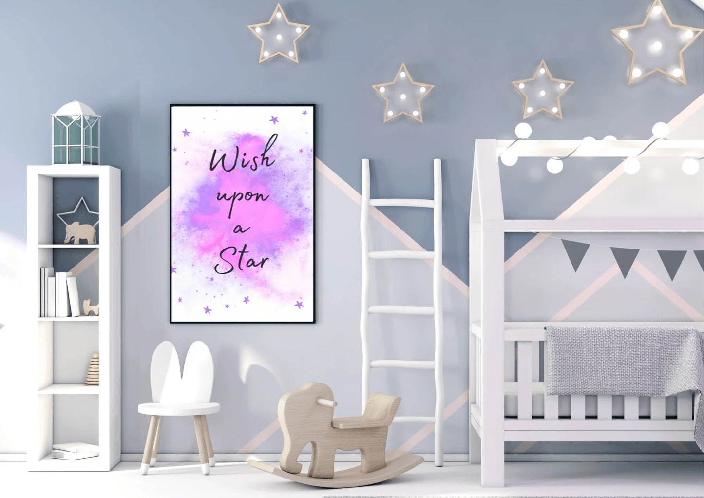 A framed "Wish upon a Star" nursery print with a purple and pink watercolor galaxy, hanging on a blue wall with a geometric pattern in a child's room with a white bed, a rocking horse, and star-shaped lights.