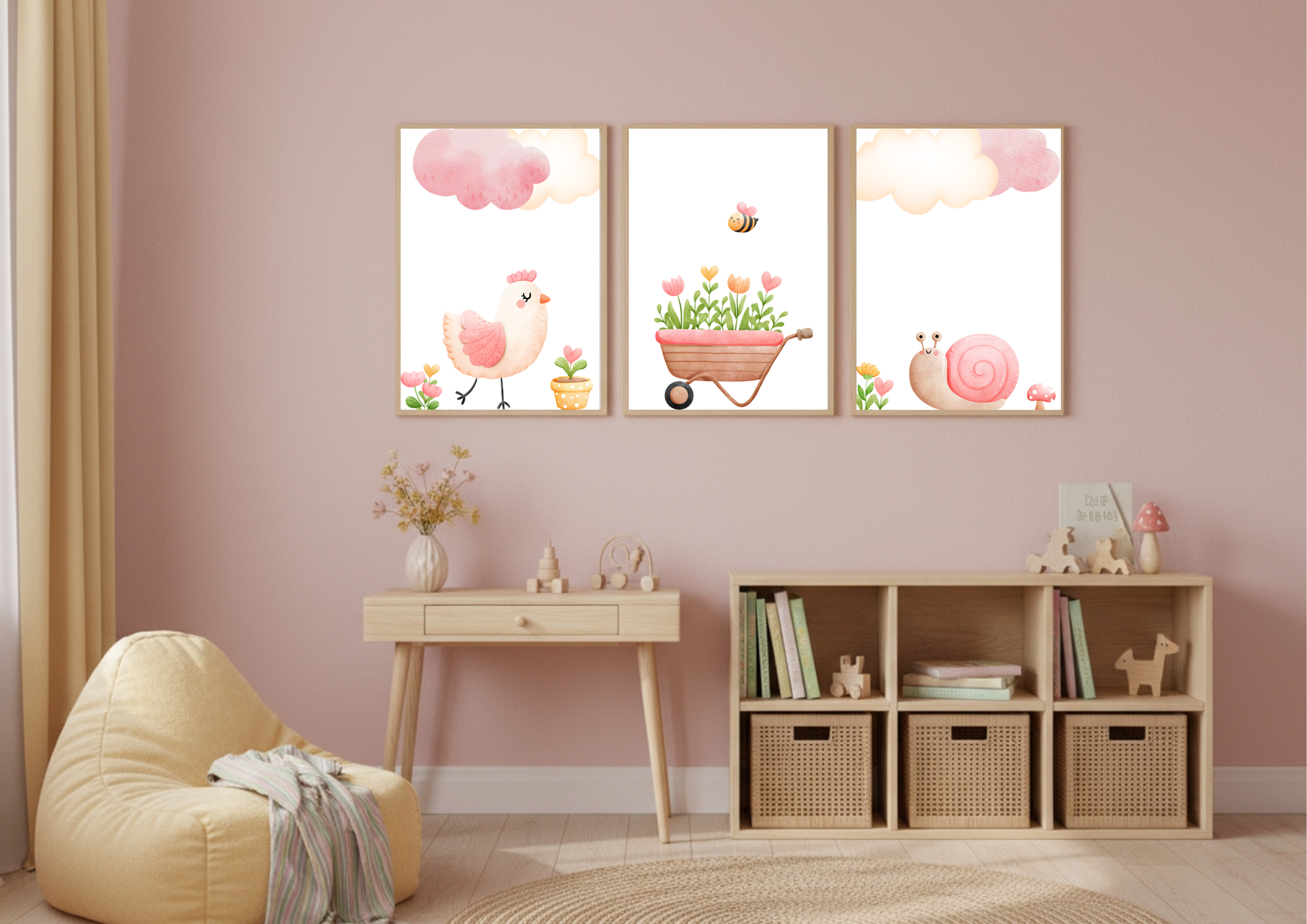 A set of three charming watercolor nursery prints displayed over a small wooden desk and cube shelf in a child's bedroom with pink walls. The prints feature a pink chick, a wheelbarrow filled with flowers and a bee, and a pink snail, all beneath pink clouds.