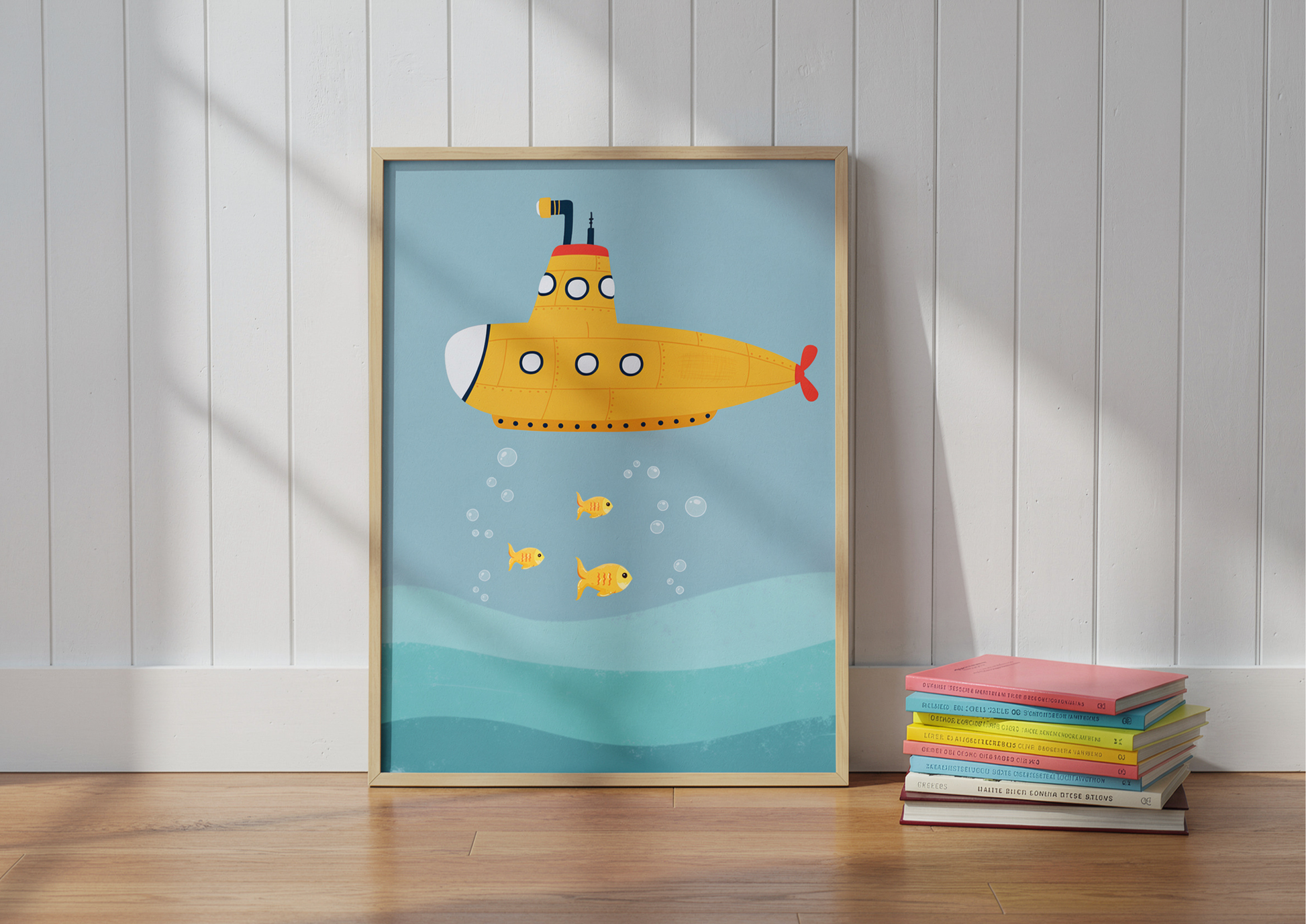 Framed illustration of a yellow submarine on a blue background, leaning against a white wall with books below.