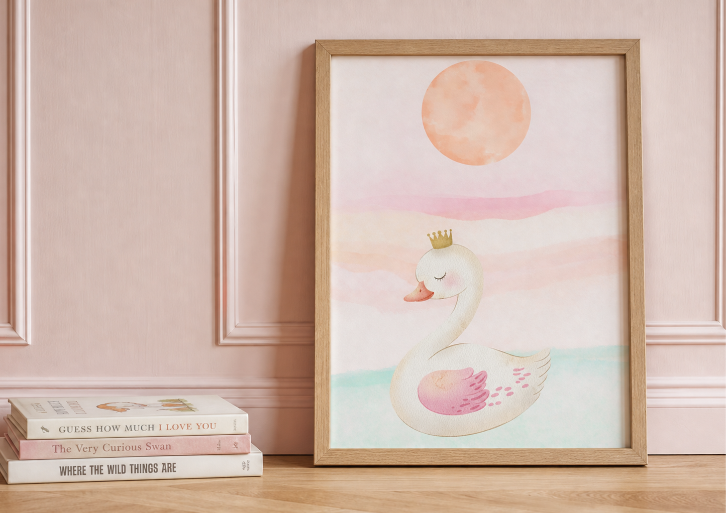 Framed watercolor nursery art print of a cute swan wearing a golden crown against a soft pastel sunset, displayed next to a stack of classic children's books.
