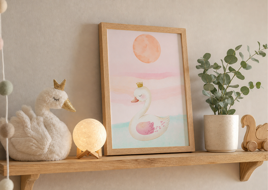 Framed watercolor nursery art print of a swan wearing a golden crown, styled on a wooden shelf next to a plush swan toy, a glowing moon lamp, and a small potted plant.
