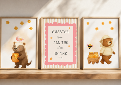 Three framed illustrations of bears with honey  on a wooden shelf with a light background