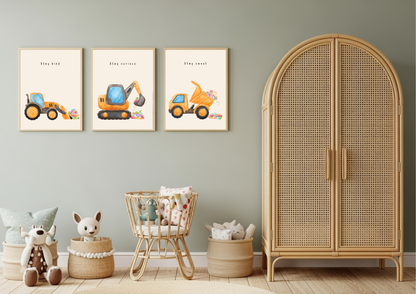 Set of three framed watercolor construction vehicle prints (Stay Kind, Stay Curious, Stay Sweet) hanging on a sage green nursery wall above a natural rattan crib and cabinet.