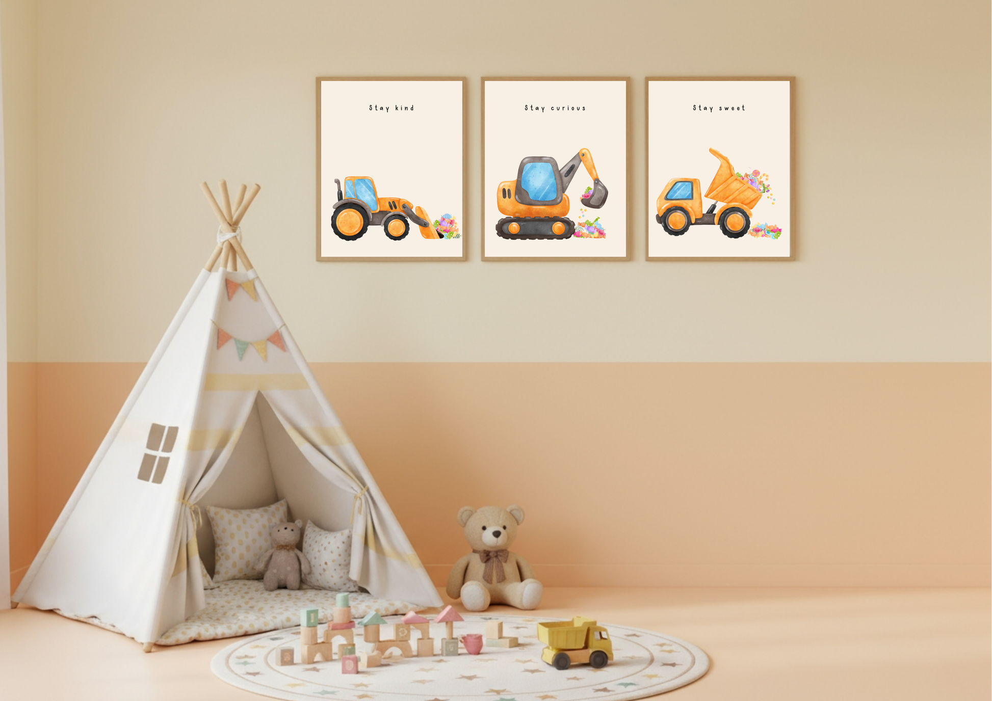Set of three framed construction vehicle prints (Stay Kind, Stay Curious, Stay Sweet) hanging above a white and yellow teepee tent in a kids' room with peach and beige walls.