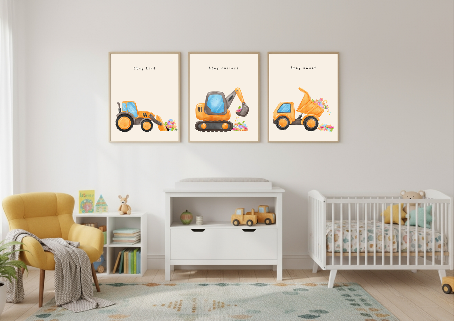 Set of three framed construction vehicle prints (Stay Kind, Stay Curious, Stay Sweet) hanging above a white changing table in a nursery with a yellow chair and white crib.