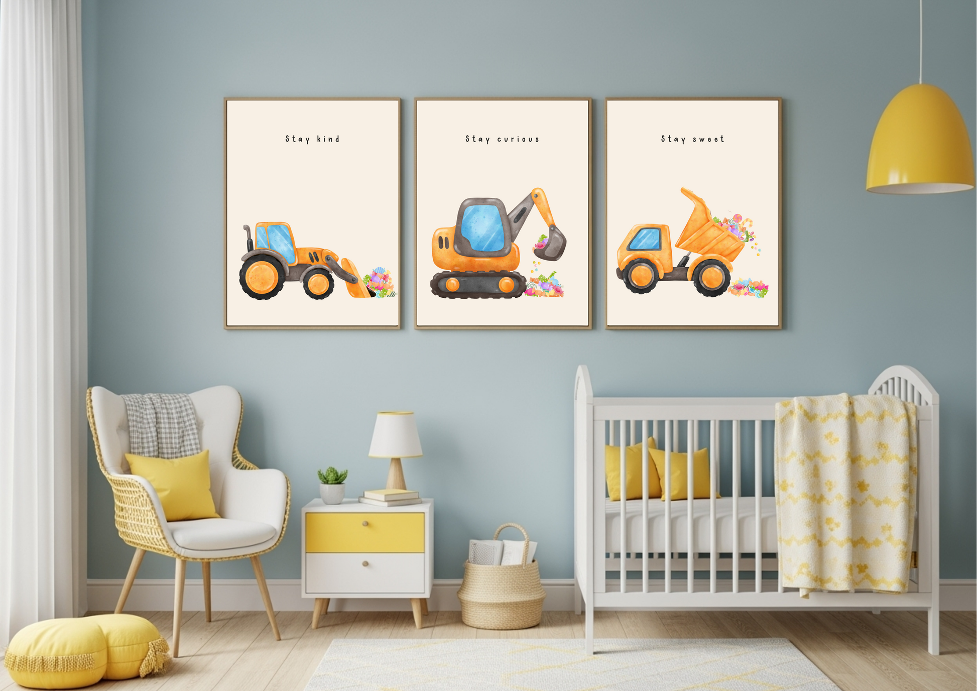 Set of three framed construction vehicle prints (Stay Kind, Stay Curious, Stay Sweet) hanging in a blue and yellow modern nursery above a white crib and rocking chair.