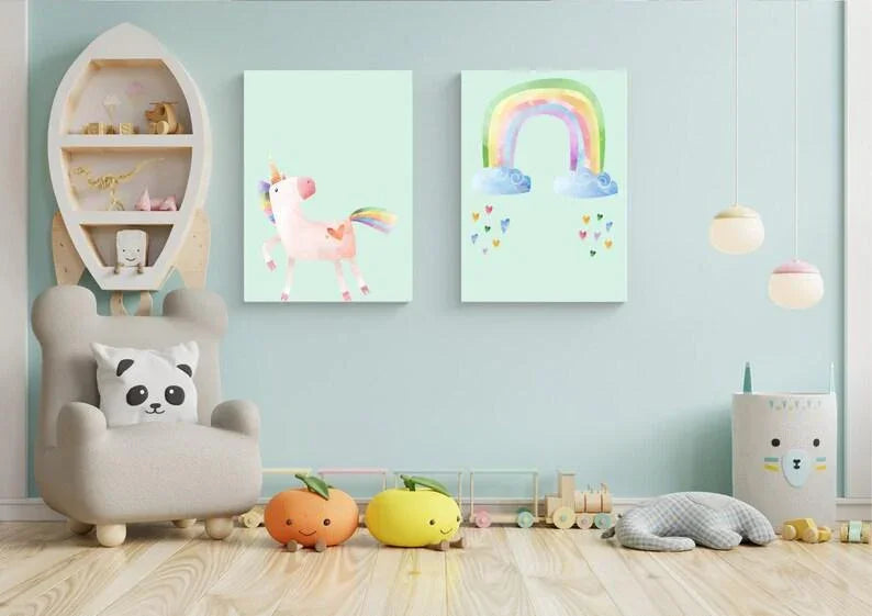 
Two unicorn and rainbow wall art prints on a blue wall in a playroom with a rocket ship shelf, stuffed animals, and wooden toys.