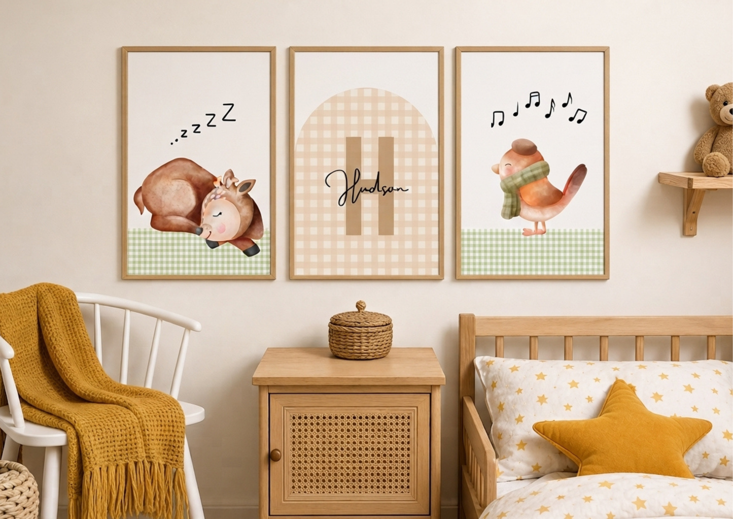 Three framed nursery wall art prints hang above a wooden crib in a styled children's room. The prints feature watercolor illustrations: a sleeping deer with 'zzz' text, a gingham arch with the name 'Hedwig', and a bird with musical notes.