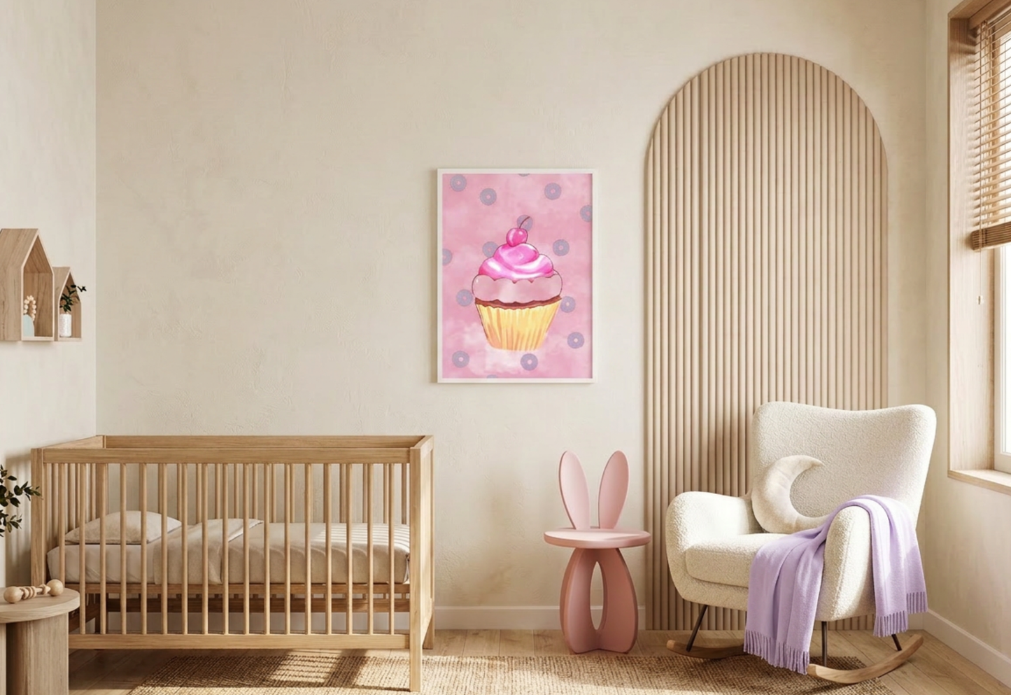 alt text
A photograph of a modern, boho-themed nursery with cream-colored textured walls and a light oak wood floor covered by a jute rug. On the left is a natural wood slatted crib, and to the right is a large beige fluted wood arched wall panel. A white boucle rocking chair sits in front of the panel, styled with a crescent moon pillow and a lavender knit throw blanket. Centrally hanging on the wall is a white-framed vertical art print featuring a whimsical pink watercolor cupcake with purple donuts.
