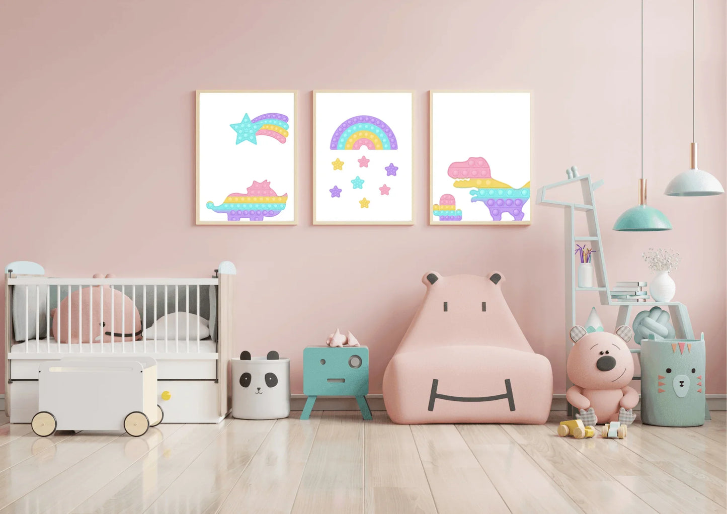 A three-piece nursery print set, featuring pop-it style dinosaurs, a rainbow, and a shooting star, hanging on a light pink wall above a crib and a pink hippo-shaped chair.