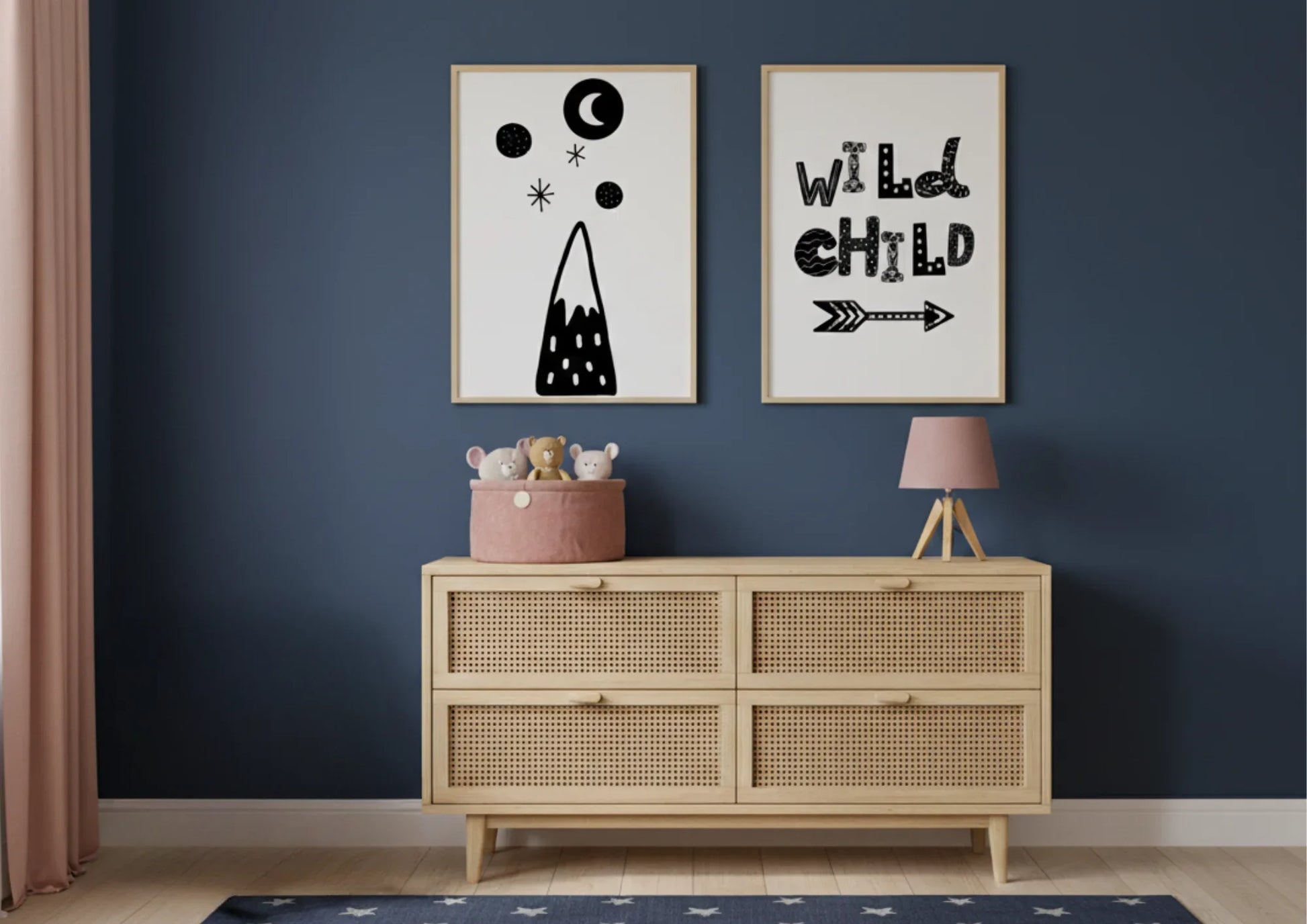 Nursery room with framed wild child artwork and wooden dresser against a dark blue wall.